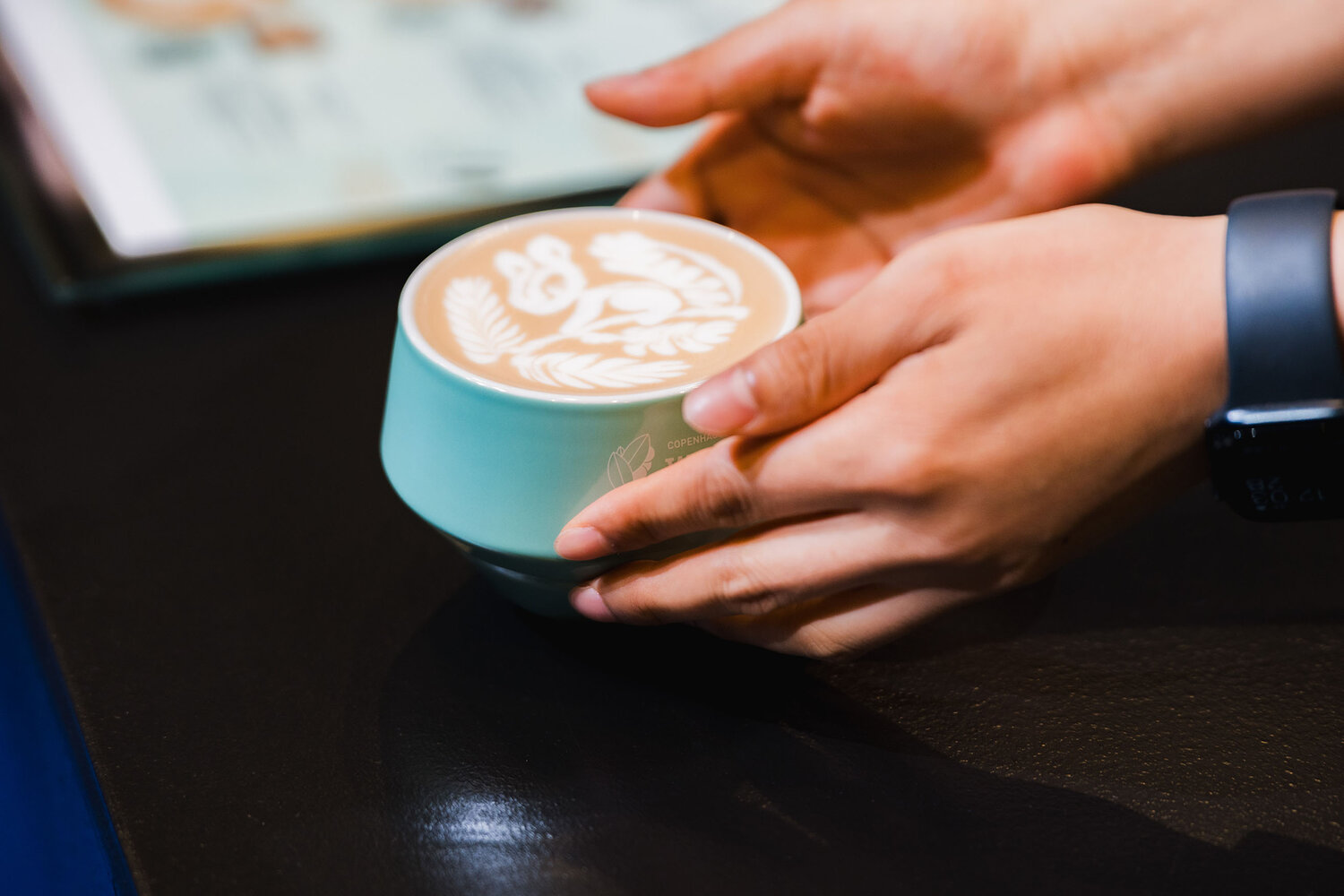 Barista pours latte art from pitcher into cup