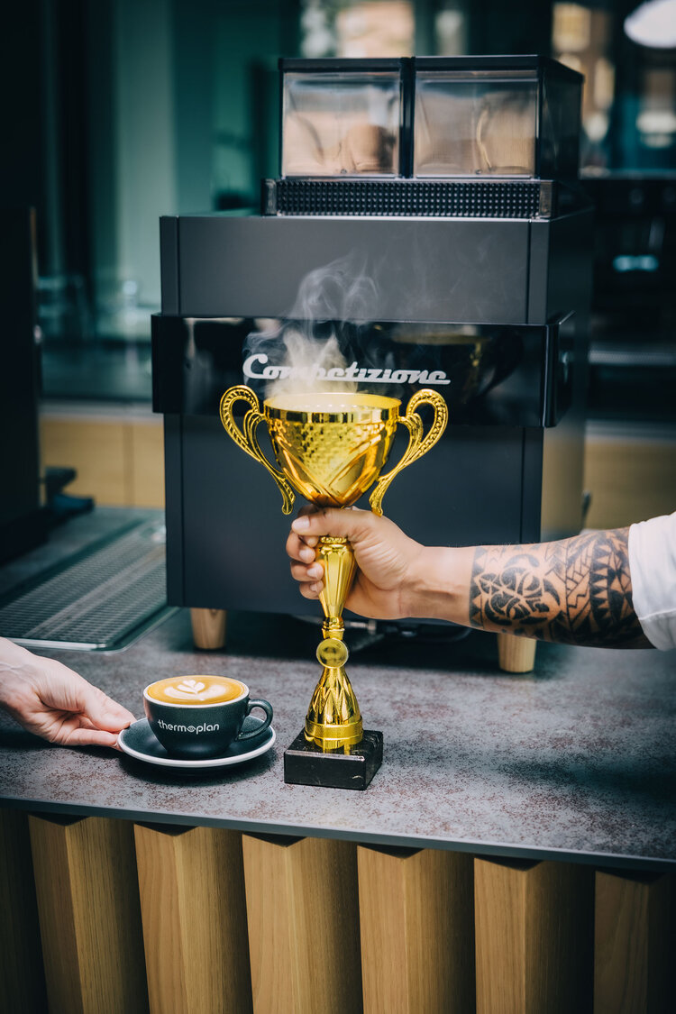 Kaffeevollautomat mit Pokal und Tasse mit Latte Art