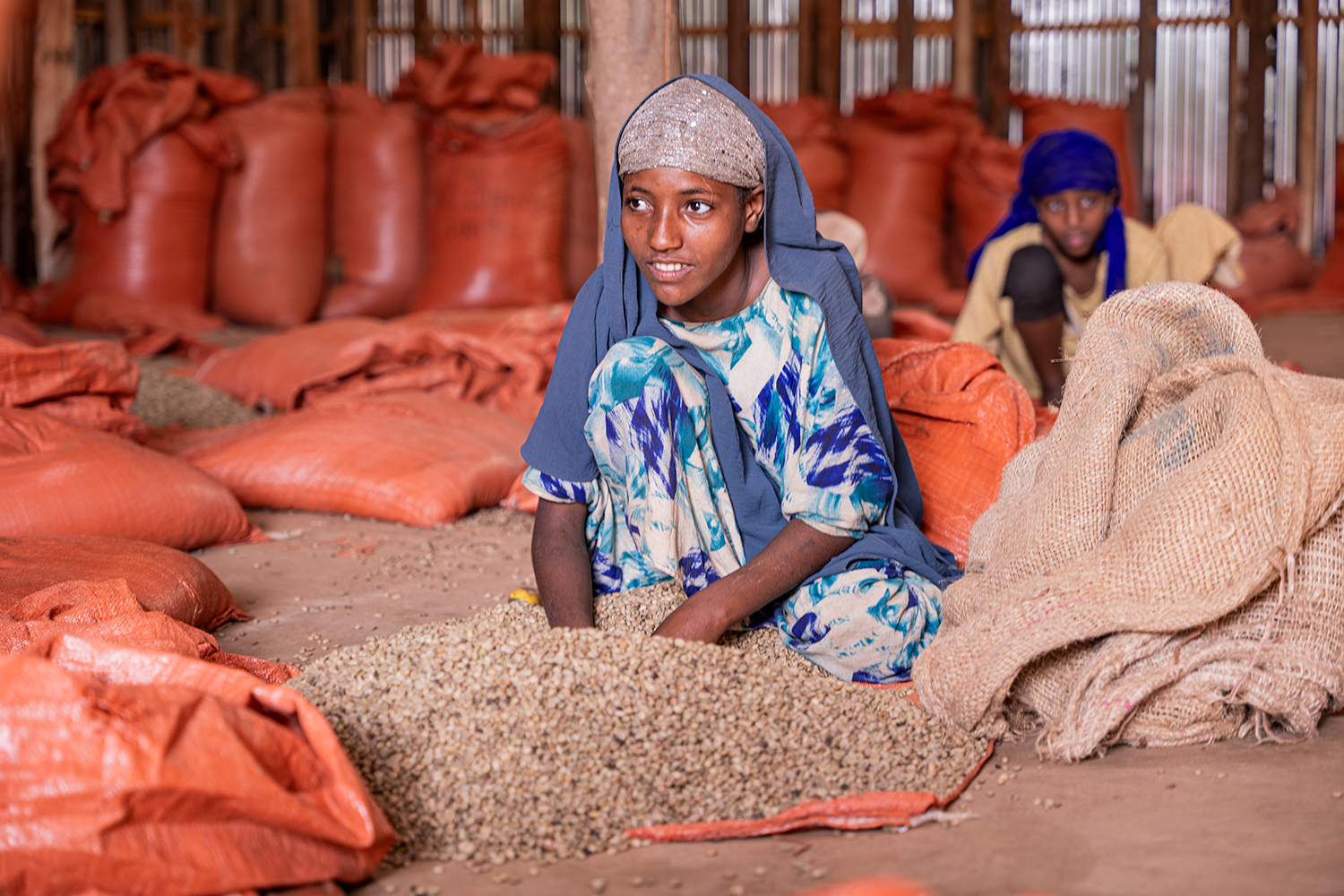 Woman working with coffee beans in front of coffee sacks in Ethiopia