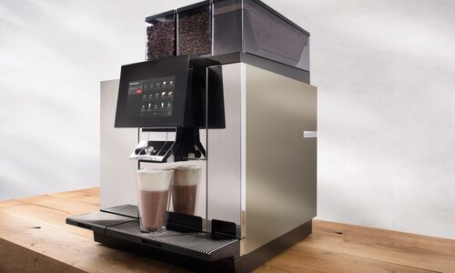Kaffeemaschine mit heisser Schokolade auf Holztisch