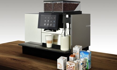 Coffee machine on wooden table with milk alternatives such as oat milk, almond milk, soy milk