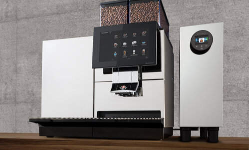 Payment module for fully automatic coffee machines on wooden table in front of stone wall