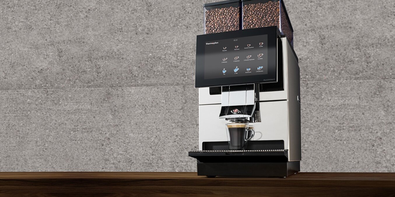 Espresso with Black&White4 fully automatic coffee machine on wooden table in front of stone wall