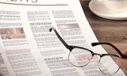 Newspaper with coffee and glasses on wooden table