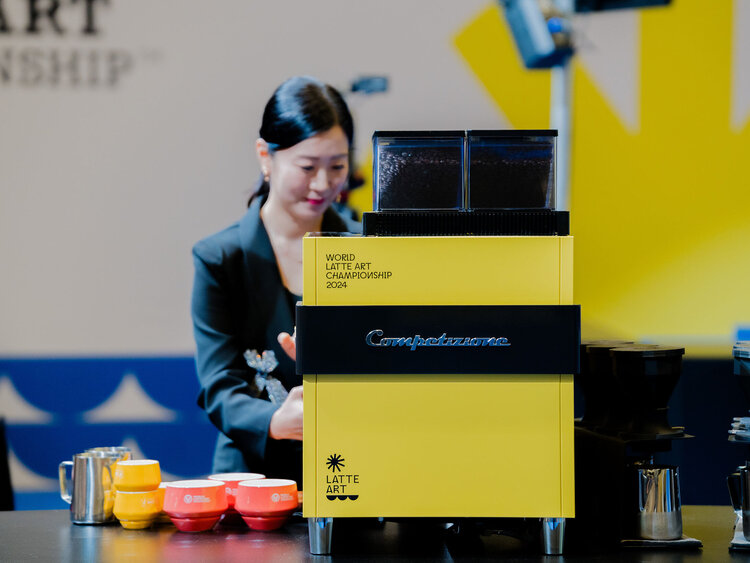 Barista schäumt Milch an Kaffeevollautomaten auf